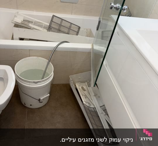 חלקי מזגן באמבטיה עם דלי מים